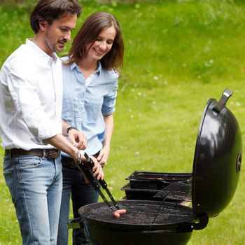 Happy couple cooking food on barbecue