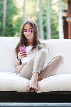 Beautiful young girl with smartphone sitting outdoors