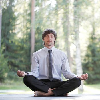 Businessman in suit practicing yoga in park