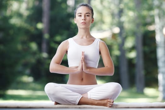 Pretty young woman doing yoga exercise in the park