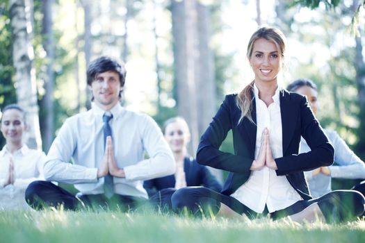 Business people practicing yoga in park