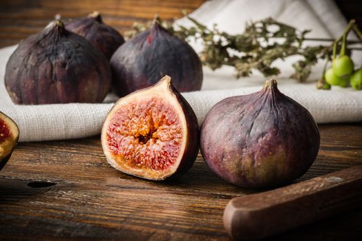 Ripe, purple figs on wooden table with sliced one fig and other things