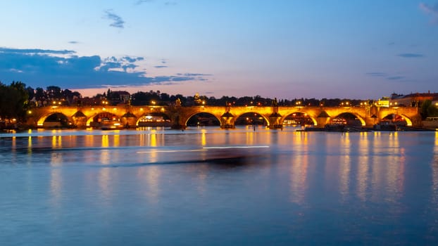 Illuminated Charles Bridge reflected in Vltava River by night. Prague, Czech Republic.