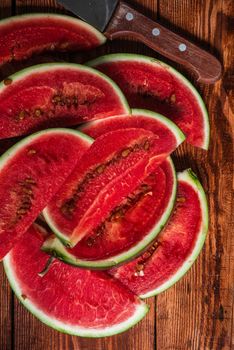 Watermelon slices with knife lying on wooden table. Vertical