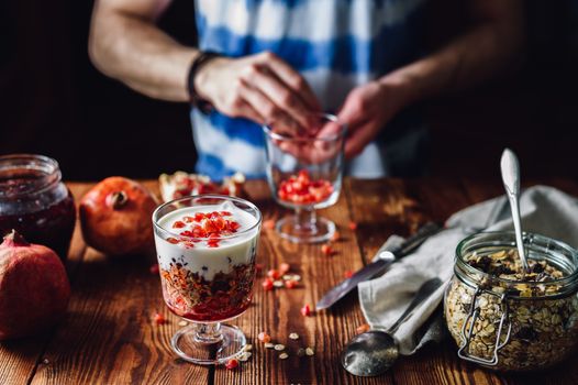 Dessert with Pomegranate and Guy Prepare New Portion on Backdrop. Series on Prepare Healthy Dessert with Pomegranate, Granola, Cream and Jam