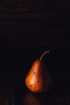 One Golden Pear on Dark Background. Vertical Photo with Copy Space