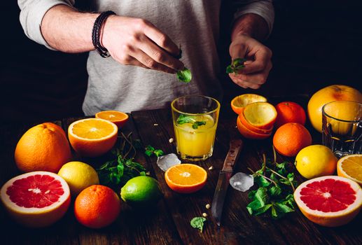 Guy Prepare the Citrus Cocktail with Ice and Mint. Some Ingredients on Table.