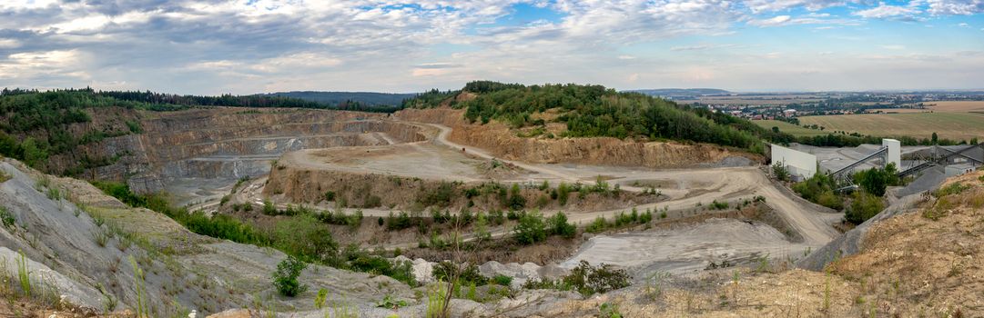 Panorama of opencast mining quarry with machinery. Quarrying of stones for construction works. Mining industry in quarry.