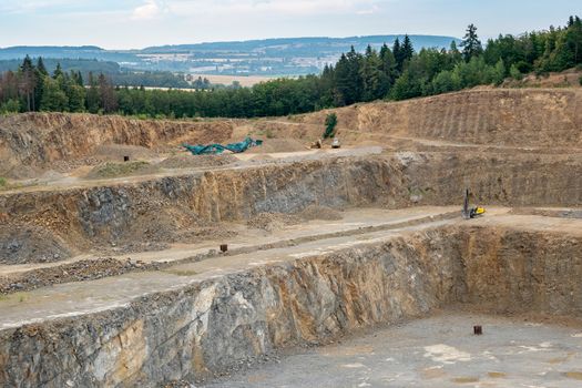 Opencast mining quarry with lots of machinery. Mining in the granite quarry. Working mining machine - digger, drilling machine. Mining industry.