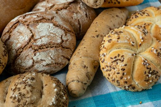 Heap of various bread rolls sprinkled with salt, caraway and sesame. Fresh rustic bread from leavened dough. Assortment of freshly of bakery products