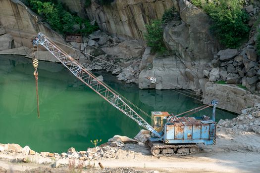 Mining in the granite quarry. Working mining machine - old crane. Mining industry.