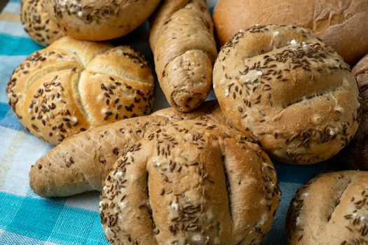 Heap of various bread rolls sprinkled with salt, caraway and sesame. Fresh rustic bread from leavened dough. Assortment of freshly of bakery products