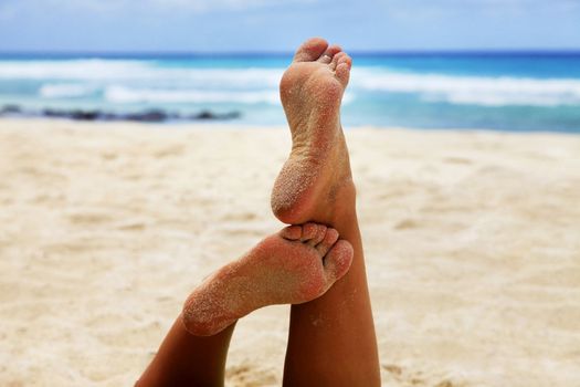 Close up of a woman feet relaxing on beach with the sea in the background