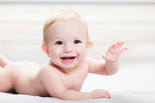 Little cute smiling newborn baby child boy hand gesturing hello or goodbye sign