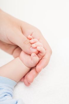 Loving mother holding newborn baby child little hand with small fingers