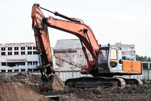 Old rusty earth digging excavator machine working at building construction site