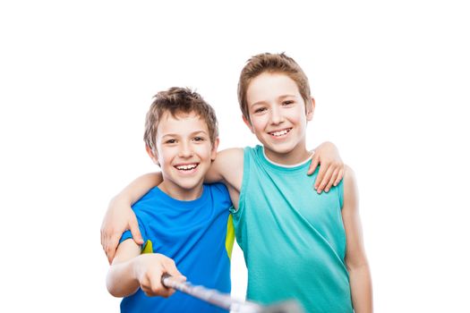 Two handsome smiling child boy brothers hand holding mobile phone or smartphone selfie stick taking portrait photo white isolated