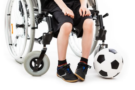 Invalid or disabled child boy sitting on wheelchair hand holding soccer sport ball white isolated