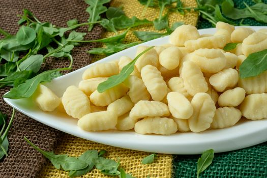 Uncooked homemade potato gnocchi in a white plate