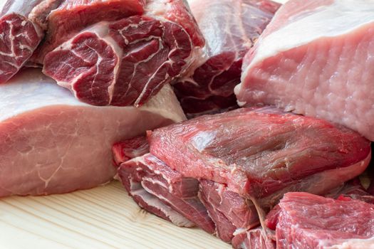 Different types of raw pork meat and beef. Raw meat on wooden table.