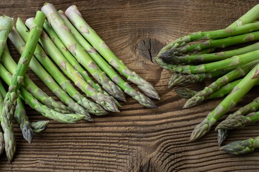 Raw garden asparagus stems. Fresh green spring vegetables on wooden background. (Asparagus officinalis).