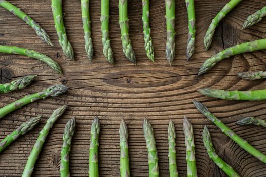 Raw garden asparagus stems. Fresh green spring vegetables on wooden background. (Asparagus officinalis).