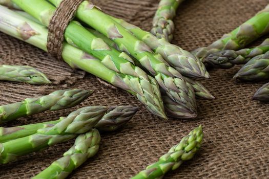 Raw garden asparagus stems. Fresh green spring vegetables on wooden background. (Asparagus officinalis).