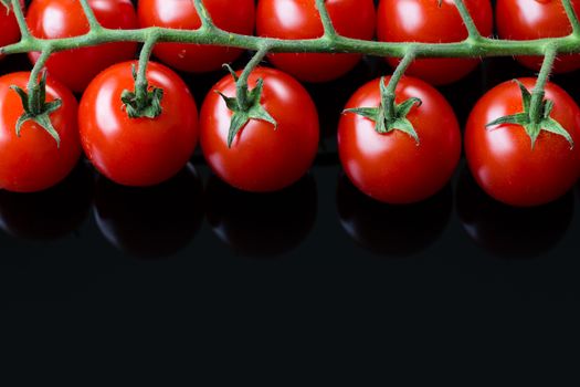 Fresh cherry tomatoes on a black background. Bunch of fresh cherry tomato on a black background