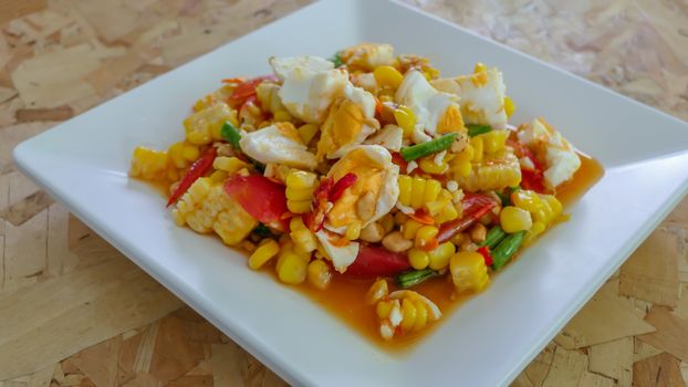 spicy sweet corn salad with salted egg on white dish