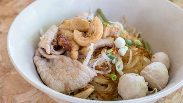 close up asian noodles with beef meatball and vegetable on wood background