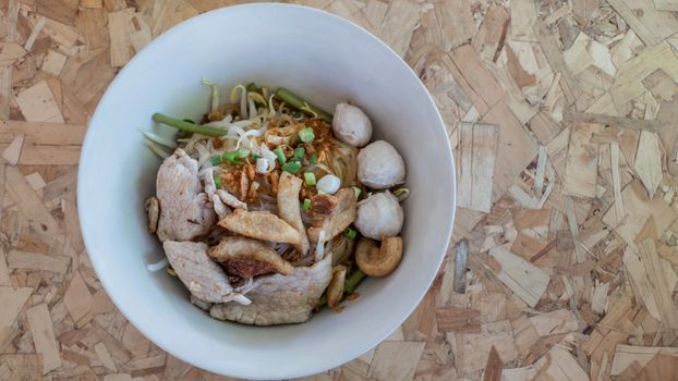 Top view of asian noodles soup with beef meatball and vegetable on wood background