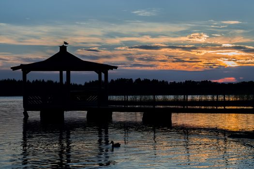 Gazebo in Lake with Mallard Duck in Water at Sunset.