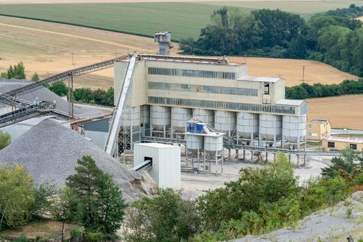 Big silos, belt conveyors and mining equipment in a quarry. Quarrying of stones for construction works. Mining industry in quarry.