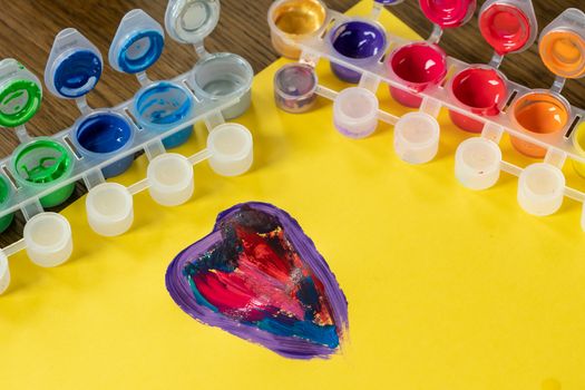 Palette mix watercolors. Children's watercolor paints. Colorful watercolor box.  Colorful heart on yellow paper.