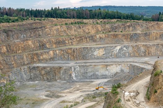 Opencast mining quarry with machinery. Quarrying of stones for construction works. Mining industry in quarry.