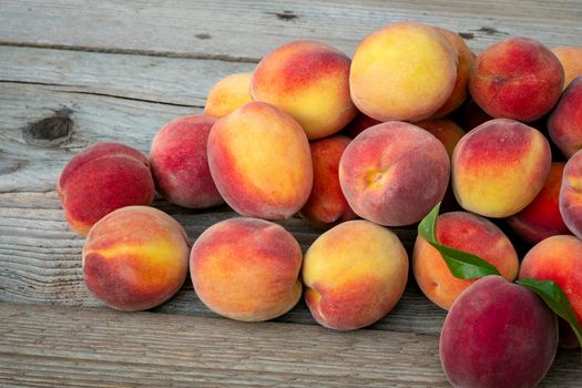 Pile of peaches. Ripe peaches fruit on a brown wooden background.
