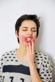 Portrait of young upset and stressed woman standing near the wall with toothache and lot of problems.