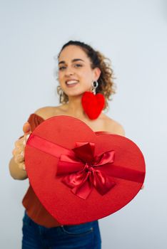 Attractive Curly Long Haired Woman Is Holding A Heart Shaped Box With Ribbon Isolated On White Background