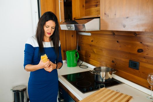 Attractive Mother In Blue Dress Preparing Spaghetti’s For the Dinner in the Kitchen