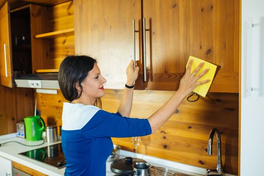 Attractive Long Haired Woman In Blue Dress Is Polishing The Kitchen With Yellow Rag