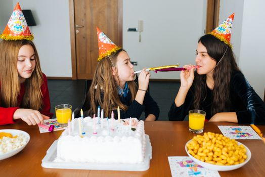 Group of kids celebrate birthday together and blowing in the whistles