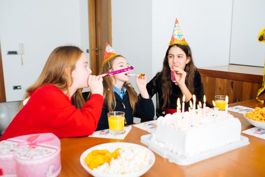 Group of kids celebrate birthday together and blowing in the whistles