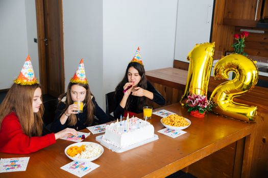 Group of kids celebrate birthday together and blowing in the whistles