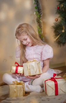 Cute girl among Christmas gifts dreaming