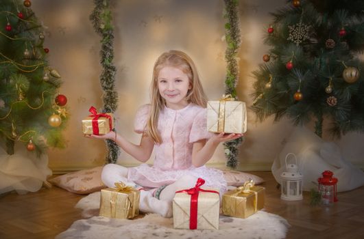 Cute girl choosing best gifts under Christmas tree