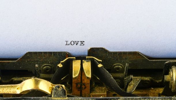 Closeup on vintage typewriter. Front focus on letters making LOVE text.   Romantic concept image with retro office tool.