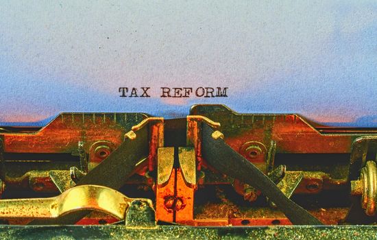 Closeup on vintage typewriter. Front focus on letters making TAX REFORM text. Business concept image with retro office tool.