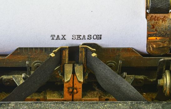 Closeup on vintage typewriter. Front focus on letters making TAX SEASON text. Business concept image with retro office tool.
