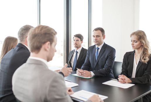 Business people discussing documents at workplace in office sitting around the table