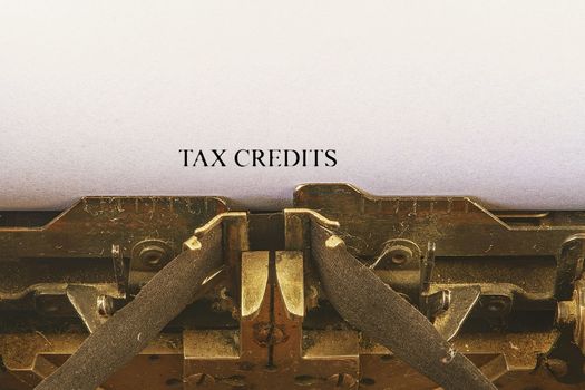 Closeup on vintage typewriter. Front focus on letters making TAX CREDITS text. Business concept image with retro office tool.